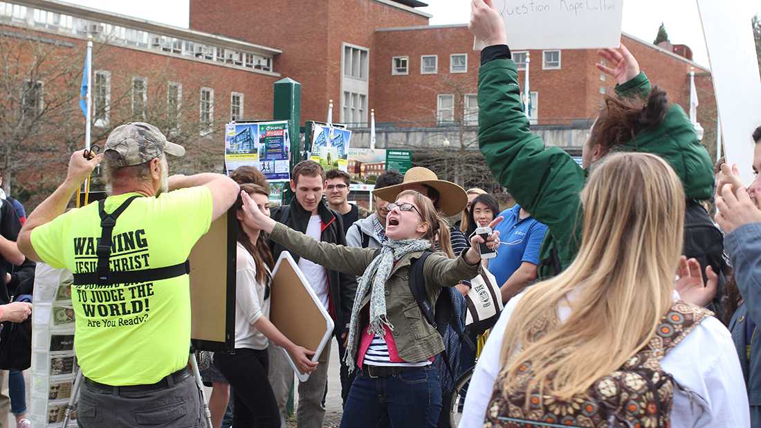 Allison Rutledge (center) was one of many students to confront a pair of anti-abortion activists at the corner of 13th Avenue and University Street on Tuesday afternoon. Following a heated debate, Rutledge and other members of the crowd snagged and scuffed up the activists&#8217; posters. (Gordon Friedman/Emerald)