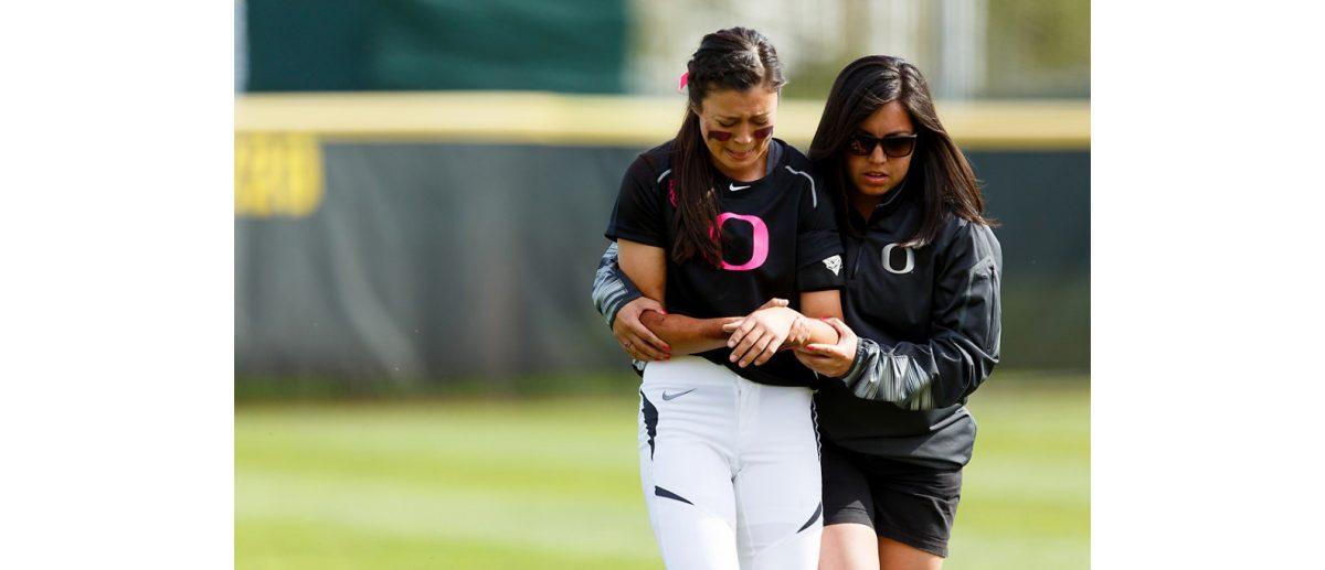 Oregon outfielder Janie Takeda (19) is walked off the field after suffering an injury during the fourth inning. The Oregon Ducks play the Washington Huskies at Howe Field in Eugene, Oregon on March 28, 2015. (Ryan Kang/Emerald)