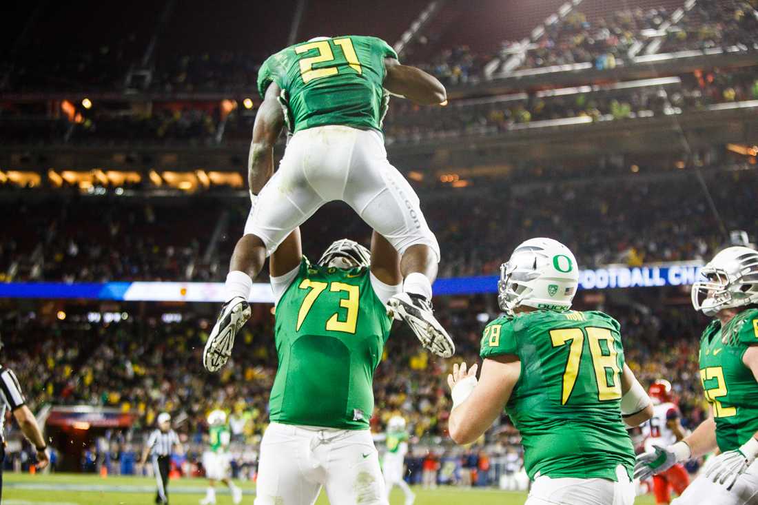 Oregon Ducks offensive linesman Tyrell Crosby (73) lifts up Oregon Ducks running back Royce Freeman (21) after running the ball more than 40 yards down the field. The play was eventually called back because of holding on the offense. The No. 2 Oregon Ducks play the No. 7 Arizona Wildcats in the Pac-12 Championship at Levi&#8217;s Stadium in Santa Clara, California on December 5, 2014. (Taylor Wilder/Emerald)