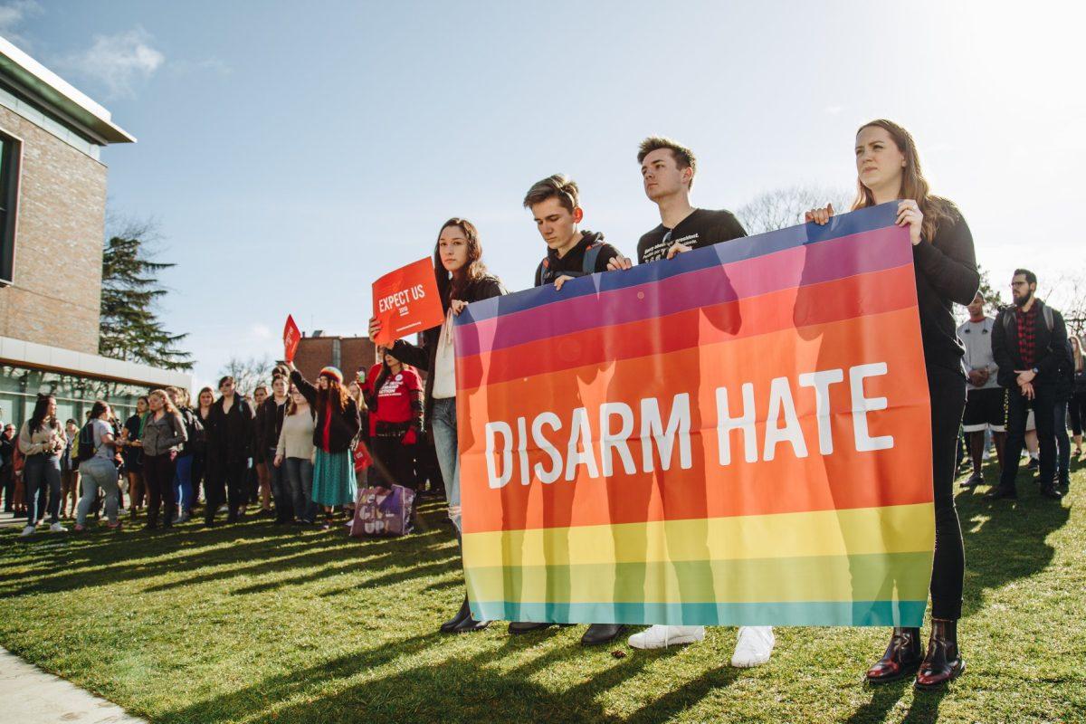 Protesters hold a sign reading &#8220;Disarm Hate&#8221; stood in front of the protest. (Sarah Northrop/Emerald)