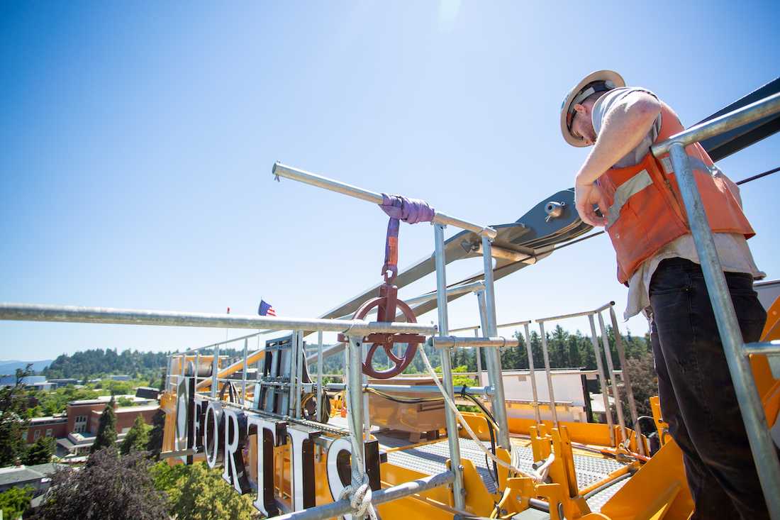 A construction workers hangs on to rails atop the crane. (Sarah Northrop/Emerald)