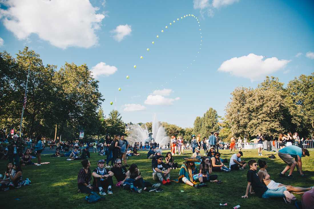 Balloons fill the sky and rainbows shine in the International Fountain as festival-goers relax in the day&#8217;s sunshine. Day two of 2018 Bumbershoot fills Seattle Center with color and excitement on Sept. 1, 2018. (Sarah Northrop/Emerald)