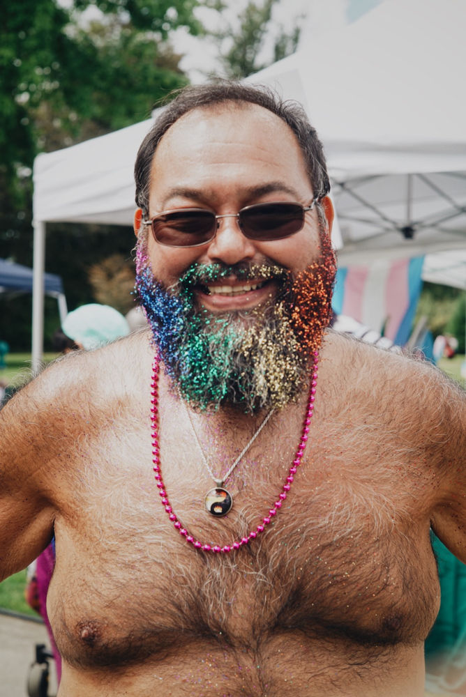 Todd Lawver shows of his rainbow glitter beard for Pride. The Pride Festival boasts a large and colorful crowd of friends, families, vendors and performers in Alton Baker Park August 11, 2018. (Dana Sparks/Emerald)