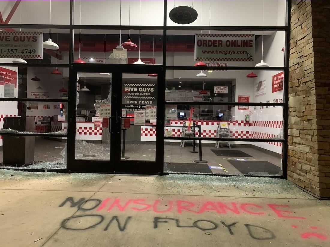 "No insurance on Floyd," graffiti says on the ground outside Five Guys on 7th Avenue in Eugene. Protestors broke windows on the business and others nearby during a demonstration Friday protesting the police killing of George Floyd. (Zack Demars/Emerald)