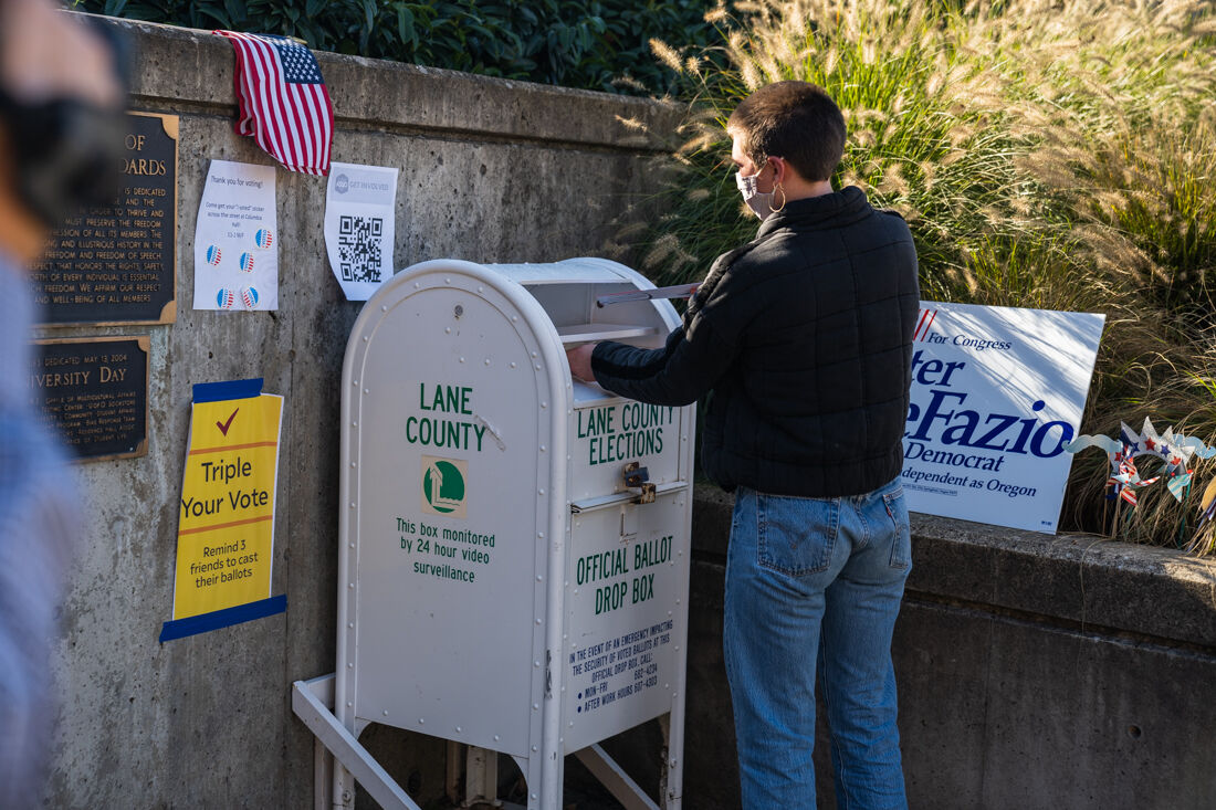 A student drops of their ballot as a demonstration of the importance of casting a vote safely. University of Oregon College Democrats host a socially distanced voting rally at the Erb Memorial Union Amphitheater in Eugene, Ore. on Nov. 2, 2020. (DL Young/ Emerald)