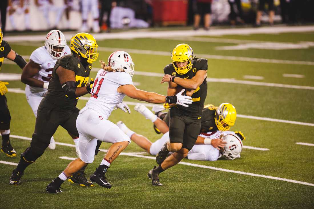 Ducks quarterback Tyler Shough (12) dodges an extended arm from a defender. Oregon Ducks Football takes on Stanford University at Autzen Stadium in Eugene, Ore. on Nov. 7, 2020. (DL Young/Emerald)