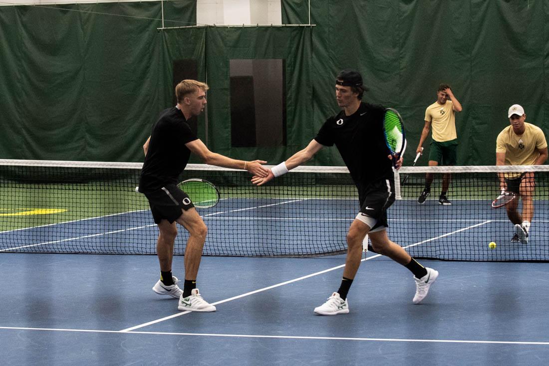 Ducks players Joshua Charlton (left) and Quinn Vandecasteele (right) high five after scoring. Oregon Ducks men&#8217;s tennis takes on the Cal Poly Mustangs at the Oregon Student Tennis Center in Eugene, Ore., on March 7, 2021. (Ian Enger/Emerald)