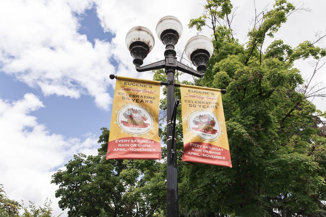 Signs welcome the public to Eugene's Saturday Market. Lane County hosts two separate farmer's markets that happen on Tuesdays and Saturdays (Maddie Stellingwerf/Emerald).