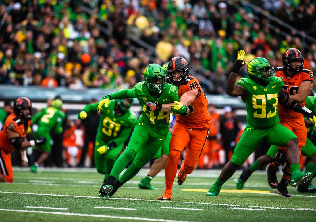 Oregon defensive end Braydn Swinson (44) charges across the field with Beavers tight end Luke Musgrave (88) clinging on to him. The University of Oregon Ducks hosted and defeated the Oregon State Beavers 38-29, claiming the Pac-12 North champions title. (Emerald/ Ian Enger)