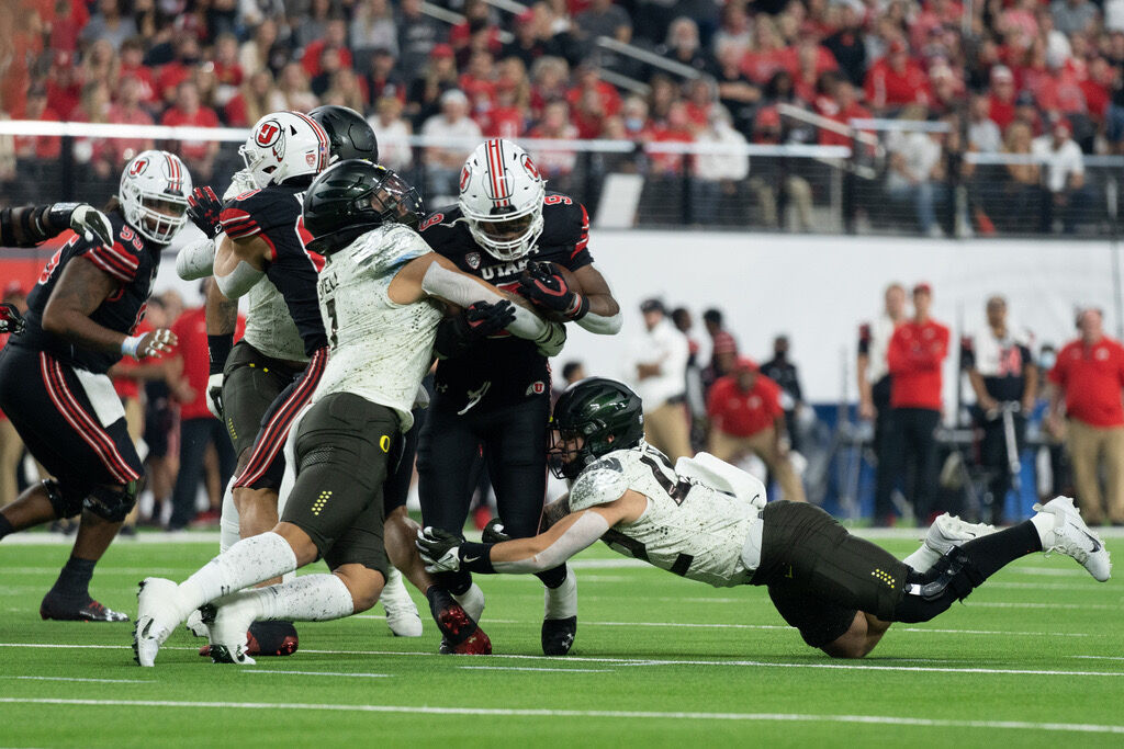 Oregon linebackers Noah Sewell and Jackson LaDuke attempt to corral Utah running back Tavion Thomas. Ducks football takes on the Utah Utes, on December 13rd, 2021, at Allegiant Stadium in Las Vegas. (Serei Hendrie/Emerald)