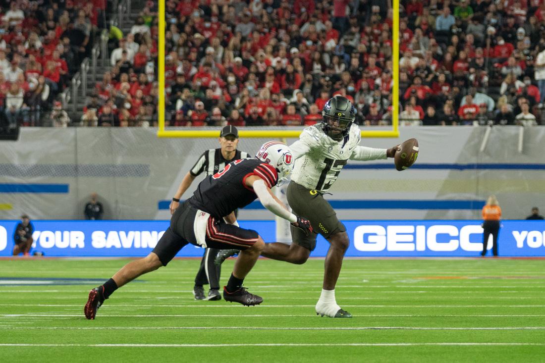 Anthony Brown Jr. (13) attempts to stiff arm an oncoming tackle to avoid a sack and a loss of yards. The Oregon Ducks take on the Utah Utes at Allegiant Stadium in Las Vegas, Nev., on December 3, 2021. (Serei Hendrie/Emerald)