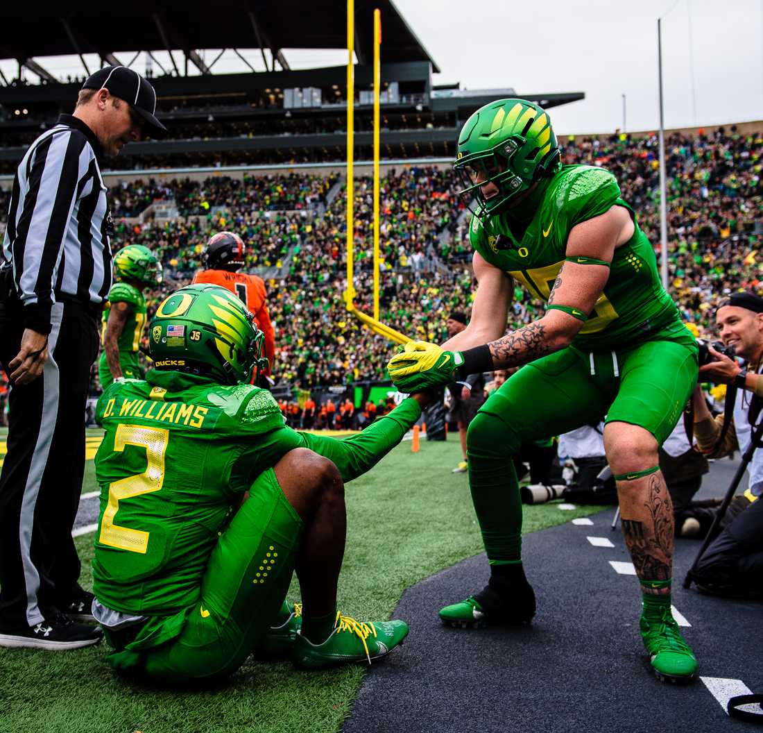 Oregon tight end Terrance Ferguson (19) helps up his teammate Devon Williams (2) after Williams was tackled into the endzone. The University of Oregon Ducks hosted and defeated the Oregon State Beavers 38-29, claiming the Pac-12 North champions title. (Emerald/ Ian Enger)