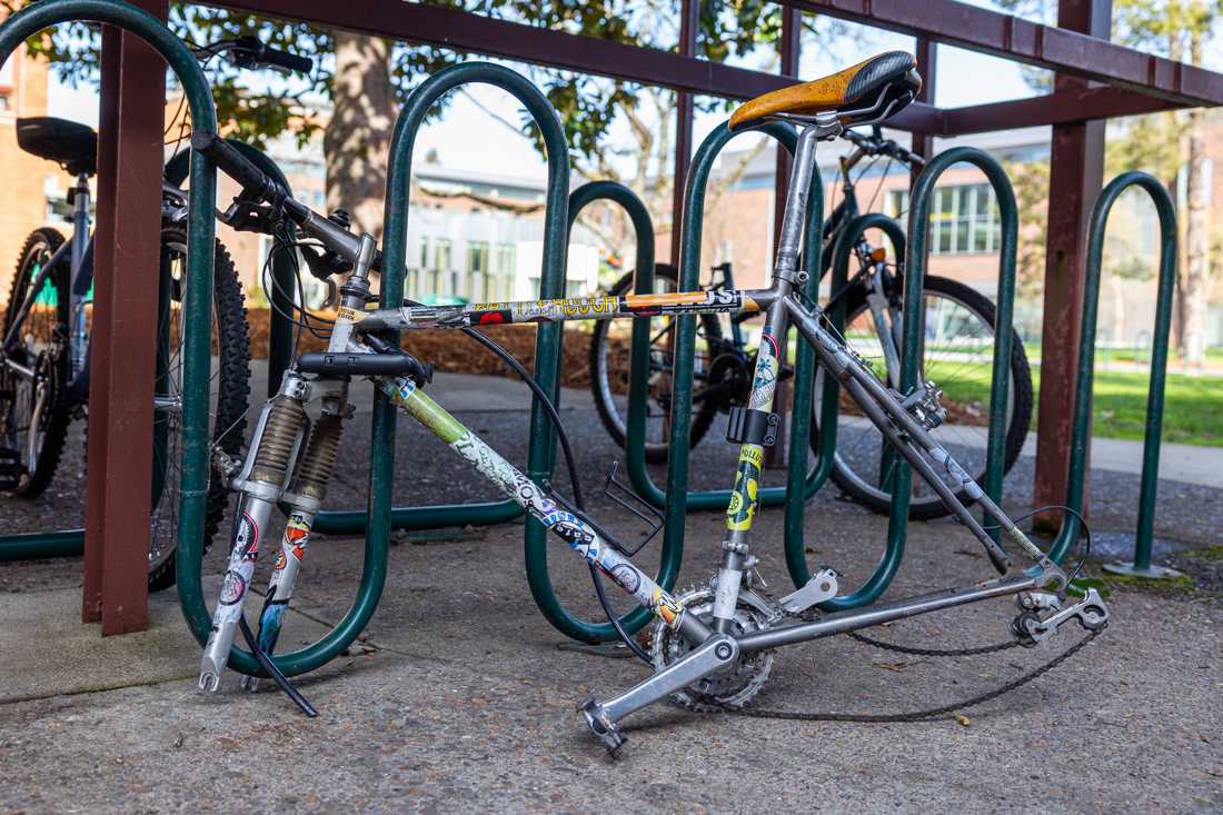 A sticker-decorated bike lays wheel-less at a bike rack. Bike theft is rampant on campus and surrounding areas; do what you can to effectively protect your bike. (Molly McPherson/Emerald)