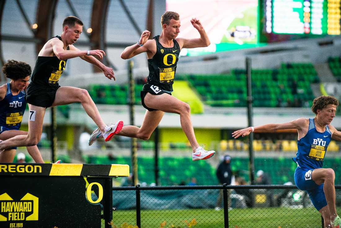 Oregon&#8217;s Quincy Norman (left) and Steve Neumaier (right) leap over a hurdle during the Men&#8217;s 3000 Meter Steeplechase. The University of Oregon hosts the annual Oregon Twilight track and field event on May sixth, 2022, at Hayward Field in Eugene, Ore. (Ian Enger/Emerald)