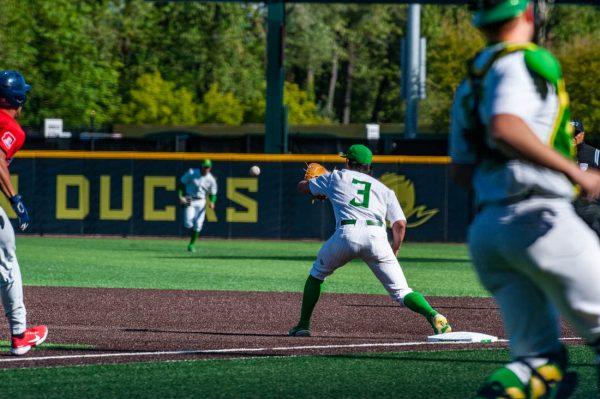 Brennan Milone (3) holds out his mit for the ball as his opponent approaches first base. Oregon Baseball takes on University of Arizona at PK Field in Eugene, Ore. on May 20, 2022. (Mary Grosswendt/Emerald)