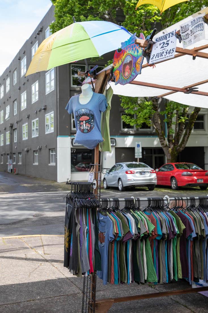 At the front of the market stands a t-shirt stand that specializes in hand drawn t-shirt designs by a local artist. The Eugene Saturday Market occurs every Saturday from 10a.m. to 4p.m. with a variety of local vendors selling everything from apparel to food. (Maddie Stellingwerf/Emerald)