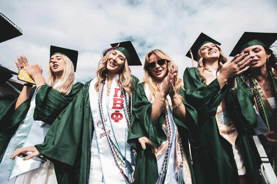 A group of graduates stand upon chairs and clap as the processions begin. University of Oregon holds its 2022 Commencement Ceremony at Autzen Stadium in Eugene, Ore., on June 13, 2022. (Maddie Stellingwerf/Emerald)