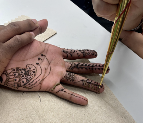 Students use a henna cone to create various designs. (Romie Avivi Stuhl/Emerald)