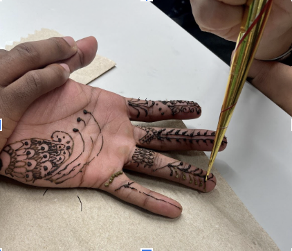 Students use a henna cone to create various designs.