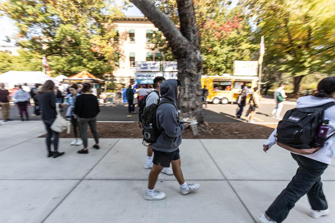 Students make their way through the faire with their food. University of Oregon students are welcomed back to campus with the annual ASUO Street Faire, a three day event filled with vendors from all across Eugene and within the University (Maddie Stellingwerf/Emerald).