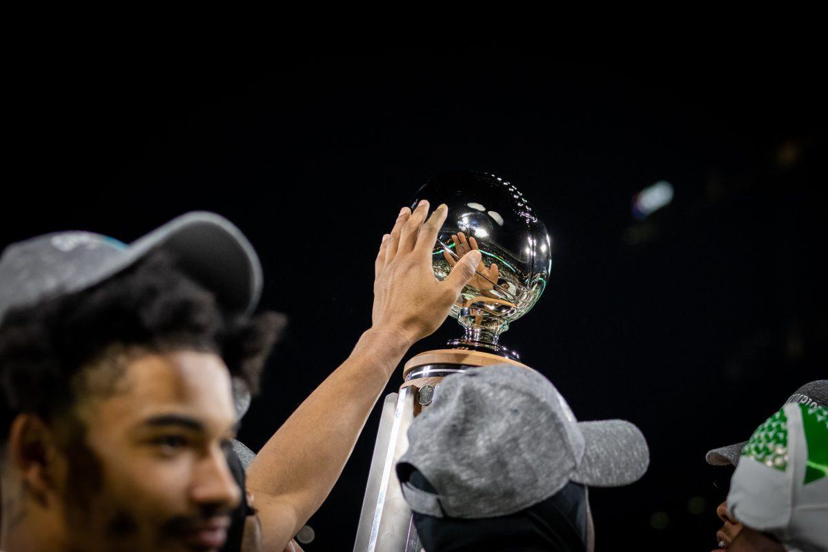 An Oregon Duck's hand reaches out to touch the Holiday Bowl trophy during the postgame celebration.&#160;The Oregon Ducks face the North Carolina Tar Heels in the annual Holiday Bowl at Petco Park in San Diego, CA, on December 28th, 2022. (Jonathan Suni, Emerald)