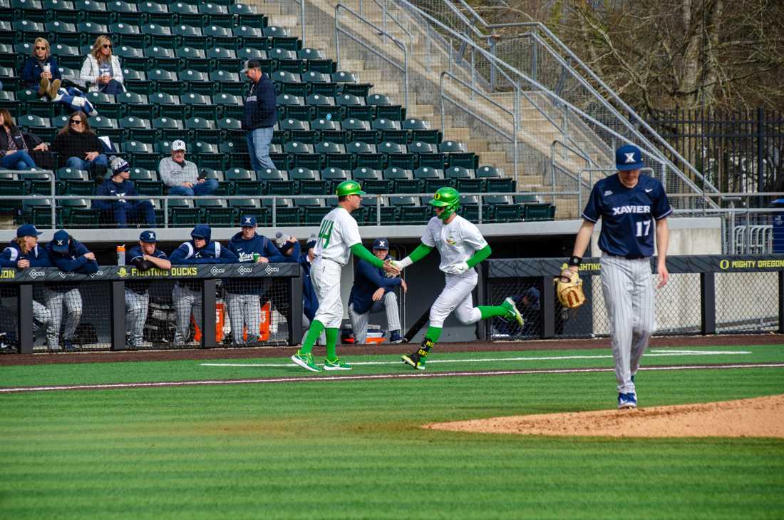 Josiah Cromwick (27) high fives Oregon Head Coach Mark Wasikowski after his first home run of the season. The University of Oregon Ducks defeat Xavier University 9-2 at PK Park in Eugene, Ore., on February 18th, 2023.(Kai Kanzer/Emerald)