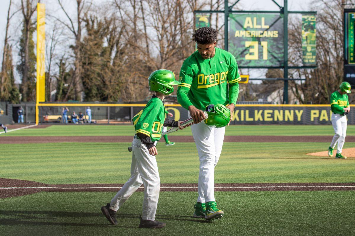 Jacob Walsh gives his bat and helmet to the team's bat kid.&#160;The Oregon Baseball team takes on Xavier for their season opening series on Feb. 19th, 2023, at PK Park. (Jonathan Suni, Emerald)