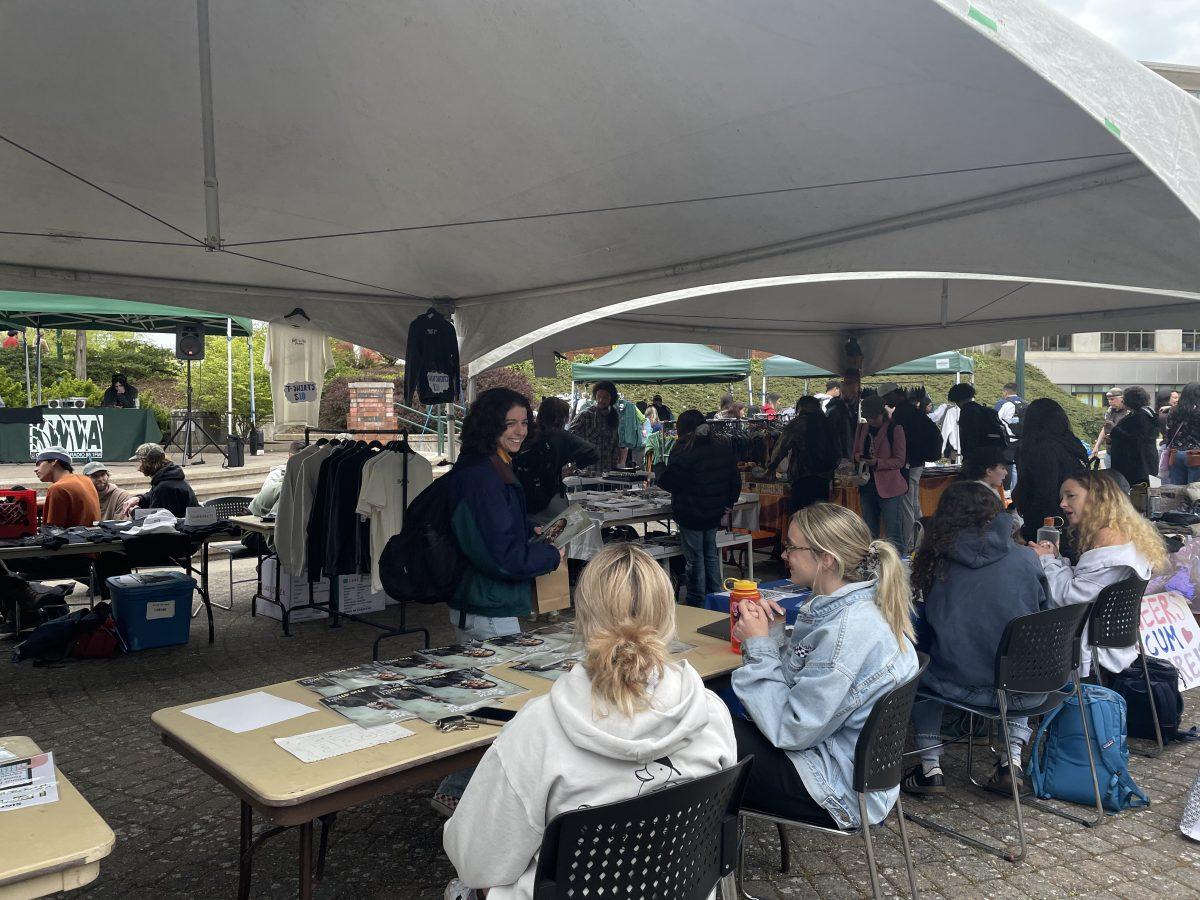 A person exchanges conversation and laughter with members of Align Magazine, a fashion and art &amp; culture magazine at the UO that tabled at the flea market. (Keyry Hernandez/Emerald)