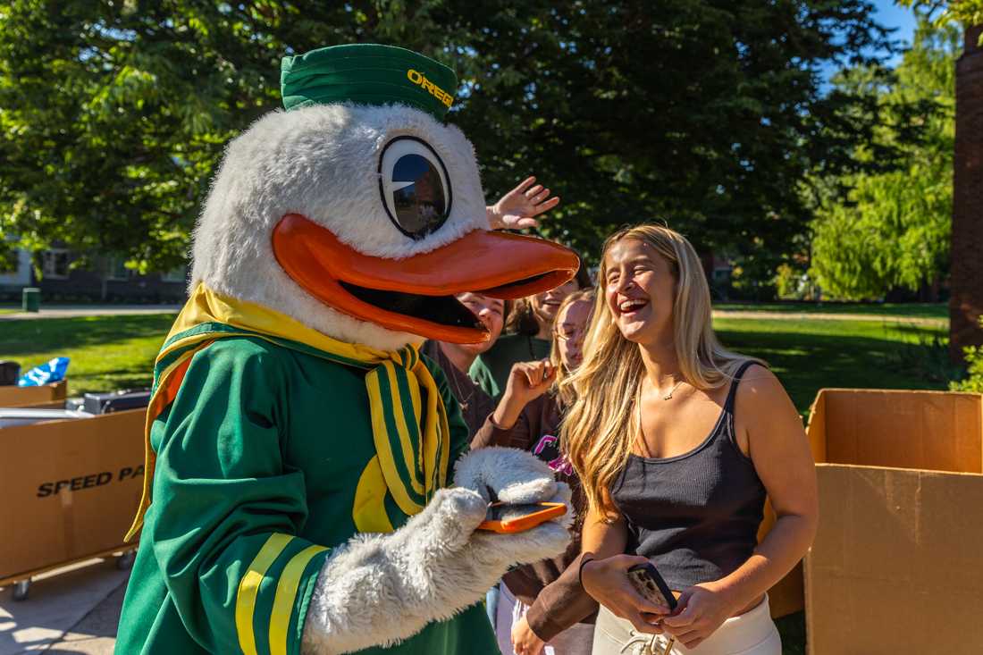 The Duck stands with a student&#8217;s phone as they laugh after The Duck takes a selfie with them. For the majority of students living on campus, fall move-in took place on Sept. 21 and 22, 2023. (Molly McPherson/Emerald)