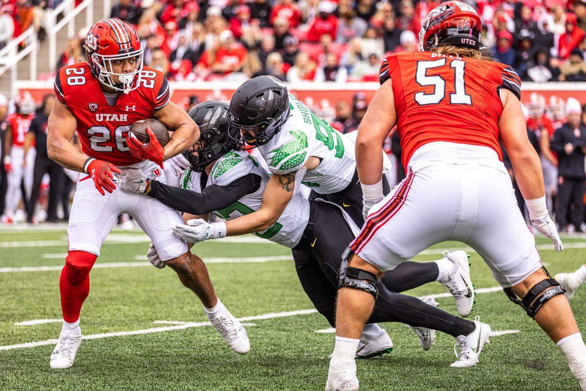 <p>Oregon's Evan Williams (33) and Jake Shipley (90) join to stop the Utah ball carrier from gaining yardage. The No. 8 Oregon Ducks defeat the No. 12 Utah Utes 35-6 at Rice-Eccles Stadium in Salt Lake City, Utah, on Oct. 28, 2023. (Jonathan Suni/Emerald)</p>