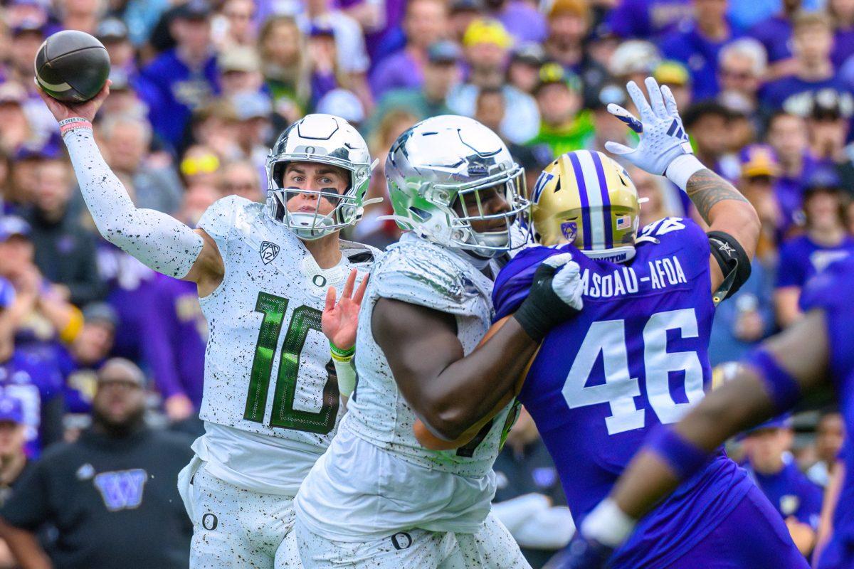 Bo Nix (10) throws the ball under pressure from Sekai Asoau-Afoa (46). The University of Oregon Ducks Football team played the University of Washington Huskies in an away match at Husky Stadium in Seattle, Washington, on October 14, 2023. (Eric Becker/Emerald)