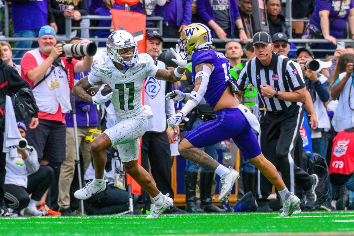 Troy Franklin (11) stiff arms a Washington defender. The University of Oregon Ducks Football team were defeated by the University of Washington Huskies in an away match at Husky Stadium in Seattle, Washington, on October 14, 2023. (Eric Becker/Emerald)