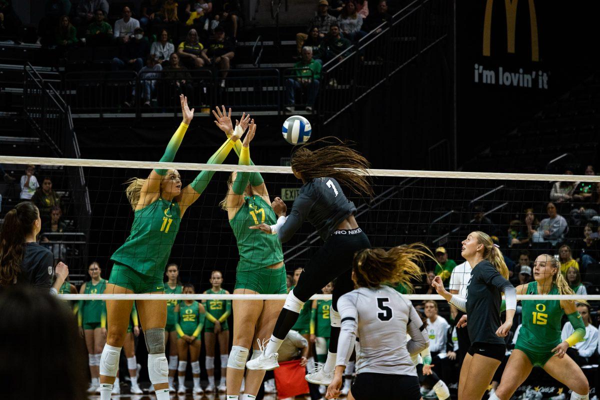 Oregon Ducks opposite Morgan Lewis (11) and middle blocker Kara McGhee (17) attempt to block a hit from Buffaloes middle blocker Skyy Howard (7). The Oregon Ducks Volleyball team defeated the Colorado Buffaloes 3-1 in a home match at Matthew Knight Arena in Eugene, Ore., on Nov. 5, 2023. (Sebastian Flores/Emerald)