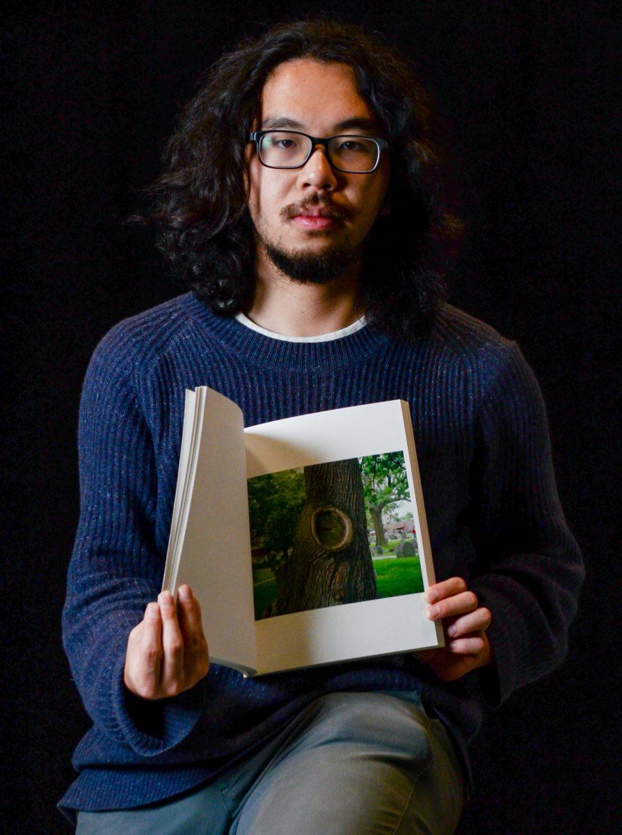 <p>Xinyu Liu flips to one of his favorite images in his softback book “The President Sang Amazing Grace.” (Kai Kanzer/Emerald)</p>