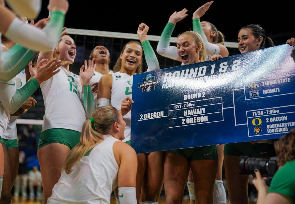 Oregon's team gathers in front of the playoff bracket to move their name forward after winning 3-0. Oregon Volleyball take on the University of Hawaii at Matthew Knight Arena in Eugene, Ore. on Dec 1, 2023. (Eddie Bruning/Emerald)