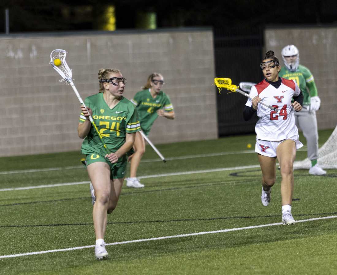 <p>Oregon midfield McKenna Cunnington carries the ball as Youngstown State attacker Ally Garrett (24) follows to defend. The Oregon Women's Lacrosse team won their match 19-8 against Youngstown State University at Pape Field on Feb. 9, 2024. (Alex Hernandez/Emerald)</p>