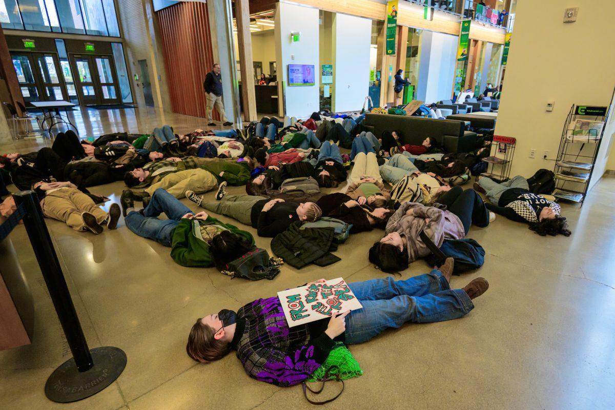 Protesters lie on the ground of the EMU behind a yellow line placed by UO staff in an attempt to keep a pathway clear. The Walkout for Palestine protest began inside the Erb Memorial Union and expanded onto the grounds of the University of Oregon in Eugene, Ore., on Feb. 21, 2024. (Eric Becker/Emerald)