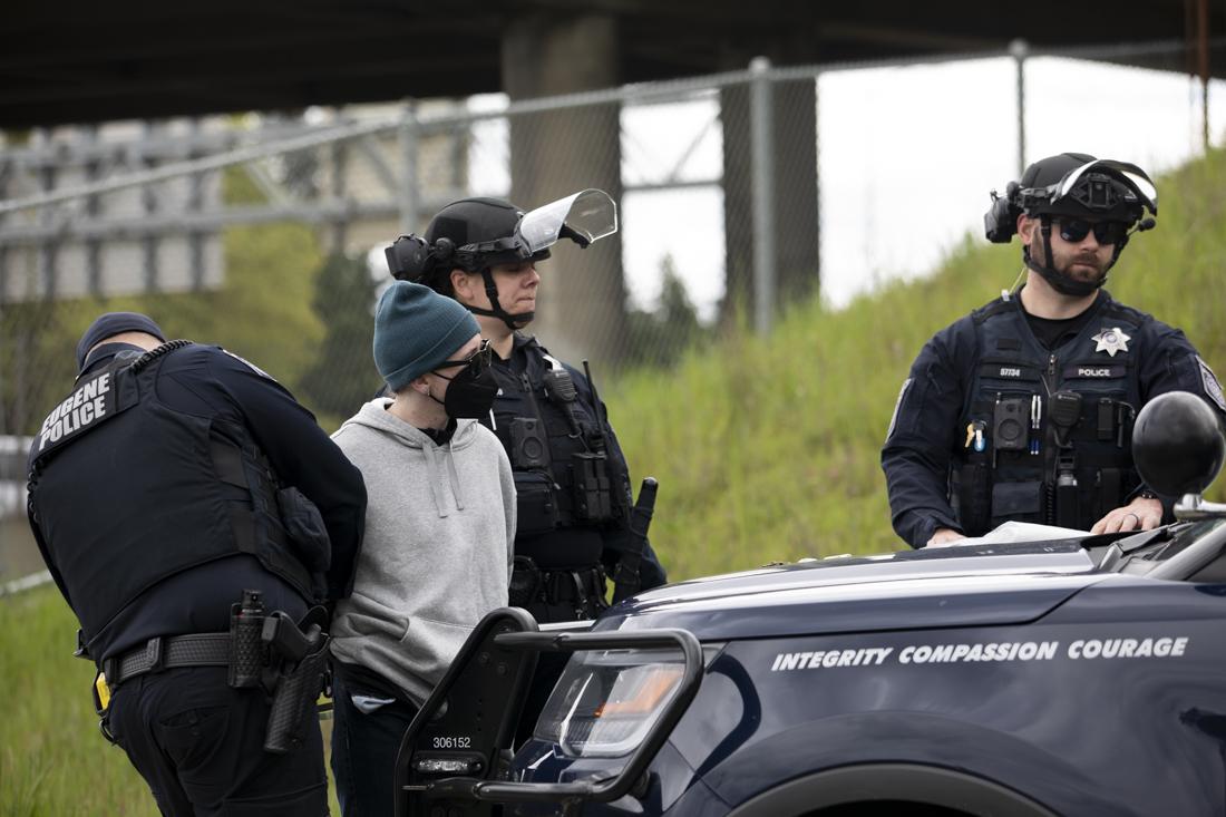 Police take an individual into custody after a protest on the I-5 on April 15, 2024. Protesters gathered on the Harlow Rd. bridge and I-5 below, blocking traffic, "as part of a global economic blockage to free Palestine," according to an Instagram post by the Springfield-Eugene Anti-Imperialist Coalition (@anti.imperialist.coalition). The demonstration was organized in conjunction with other actions across the world as part of the "A15 Economic Blockades for a Free Palestine." (Alex Hernandez/Emerald)