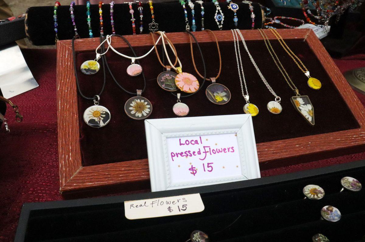 Pressed flower jewelry crafted by Negar Tahmidi, on display to be purchased at the Eugene Saturday Market. (Alyssa Garcia/Emerald)