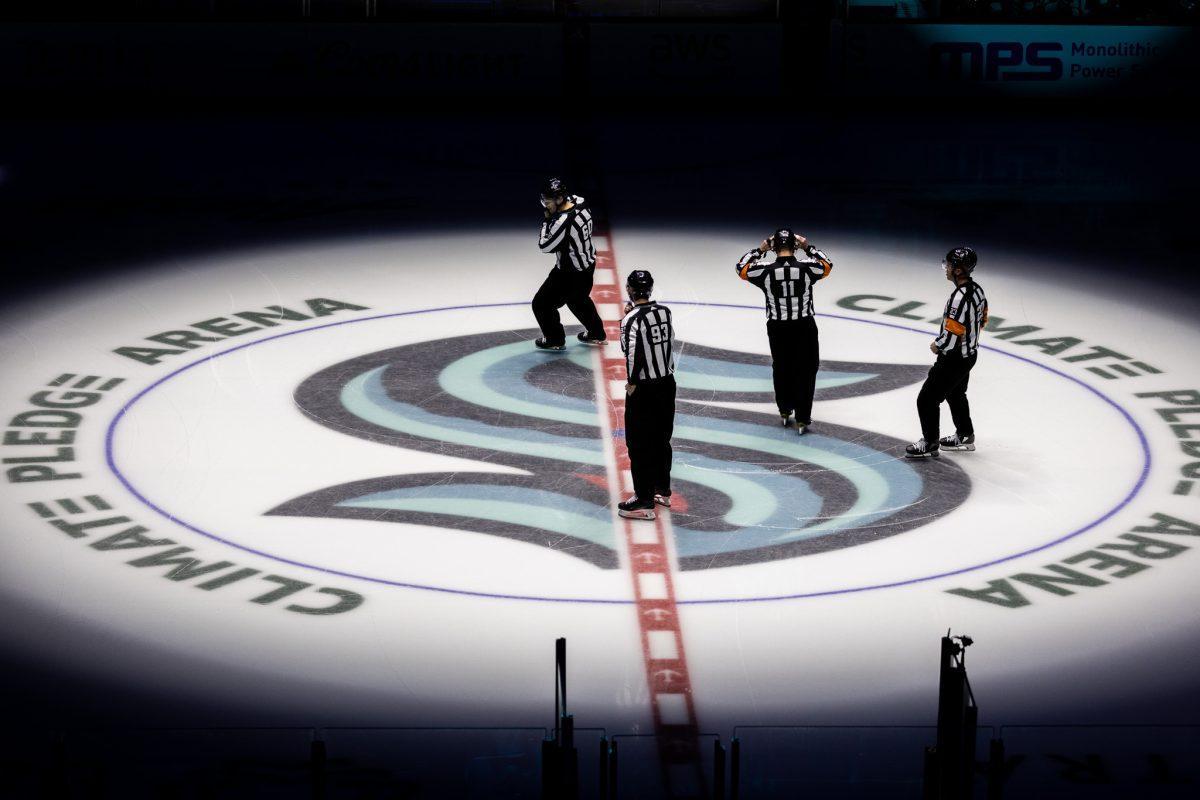 The officials meet at center ice as the home team crowd welcomes the Seattle Kraken onto the ice. The Seattle Kraken host the Dallas Stars at the Climate Pledge Arena in Seattle, Wash., on March 30, 2024. (Jonathan Suni/Emerald)