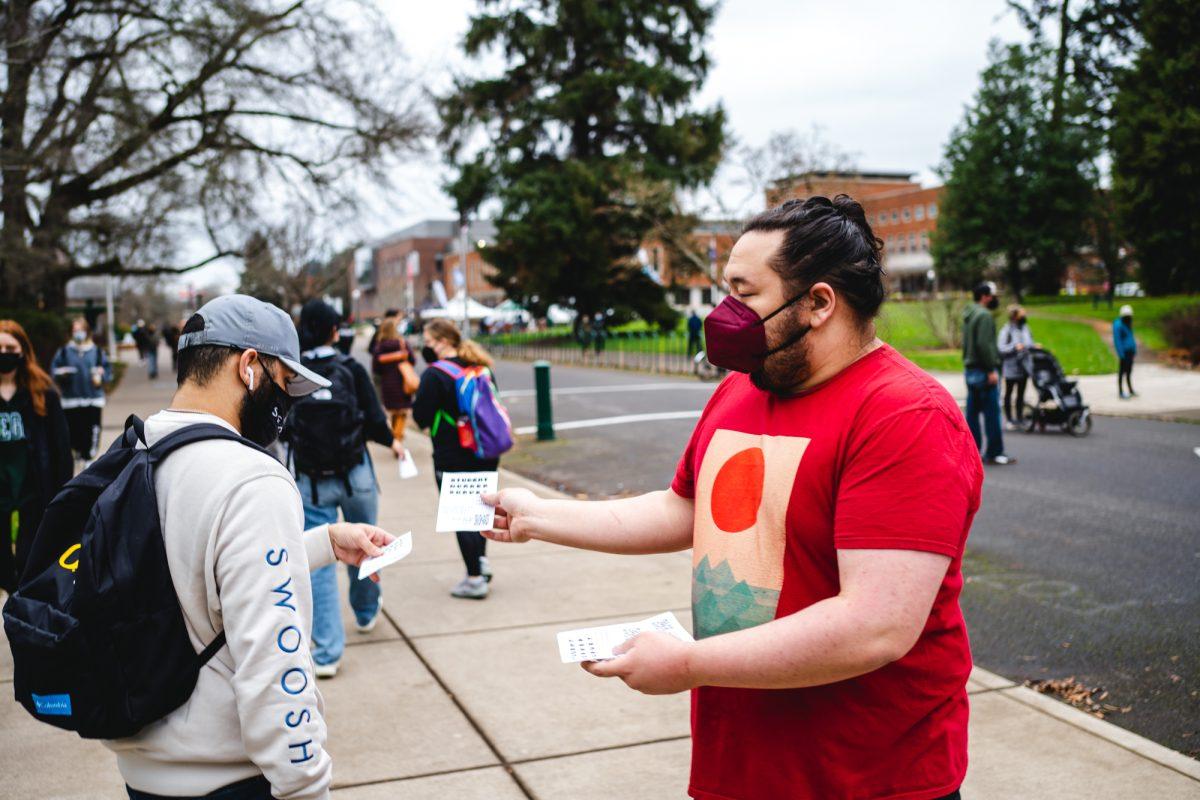 <p>Max Jensen (right), a member of the Young Democratic Socialists of America, hands out flyers during a 2022 GTFF protest on campus. Jensen is running for ASUO president in the 2024 presidential election on the UO Student Power slate. (Will Geschke/Emerald)</p>