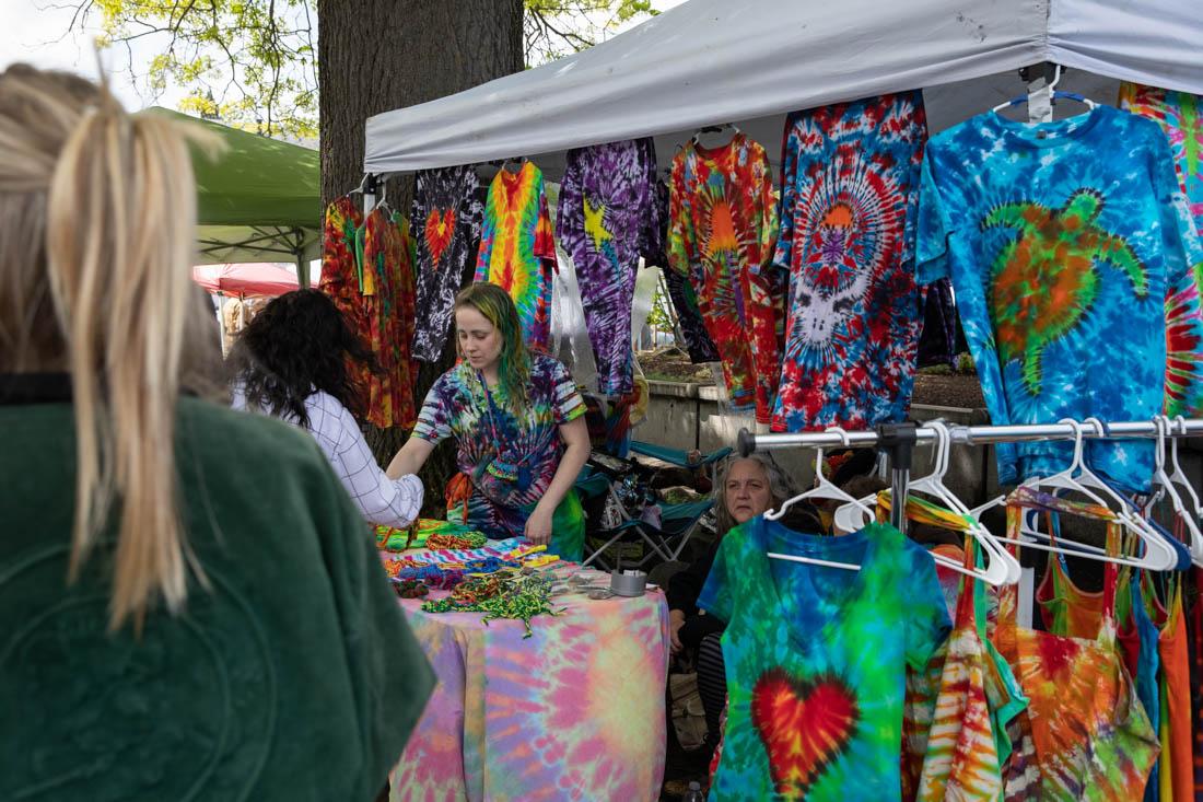 A booth dedicated to tie-dye apparel makes a sale to a customer of the market. The Eugene Saturday Market occurs every Saturday from 10a.m. to 4p.m. with a variety of local vendors selling everything from apparel to food. (Maddie Stellingwerf/Emerald)