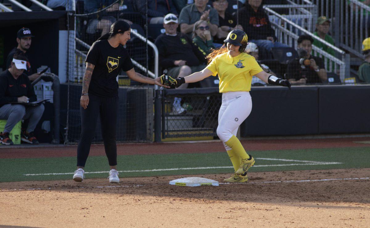 Vallery Wong (99) passes batting gear to Assistant Coach Alyssa Palomino-Cardoza after being walked. The Oregon Softball team secures the win 11-3 over Oregon State in game 1 of their Rivalry Series, hosted at Jane Sanders Stadium in Eugene, Ore., on April 19, 2024. (Alyssa Garcia/Emerald)