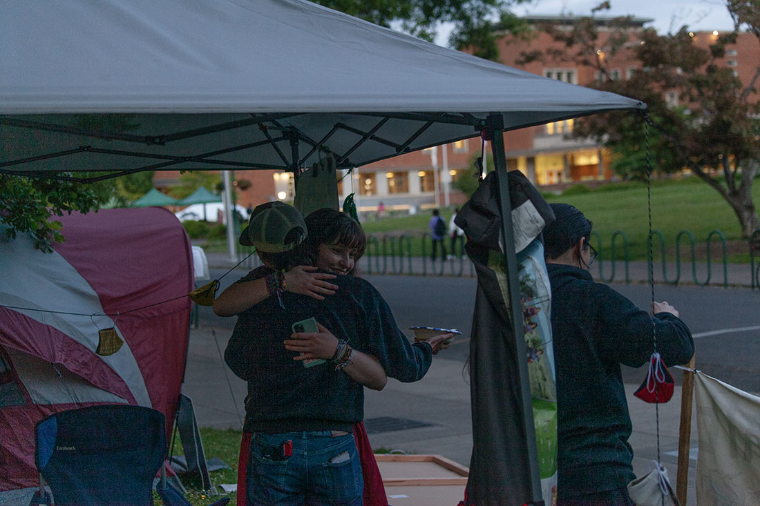 Two protestors embrace while the encampment packs up. Encampment negotiators reached an agreement with UO President John Karl Scholtz Wednesday night to take down the encampment outside of Johnson Hall in exchange for meeting some of the demonstrators' demands. As part of the agreement, any students charged with violating university code of conduct policies will receive amnesty. The encampment started on April 29 at the Memorial Quad and later moved outside Johnson Hall on May 16. (Miles Cull/Emerald)