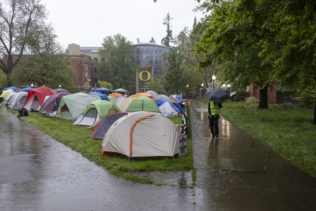 A demonstrator patrols the edges of the encampment on May 3, 2024. This is the fifth day of the growing pro-Palestine encampment demonstration, which now fills most of space between Lillis Business Complex and Knight Library; the protest is one of many across college campuses nationwide. (Alex Hernandez/Emerald)