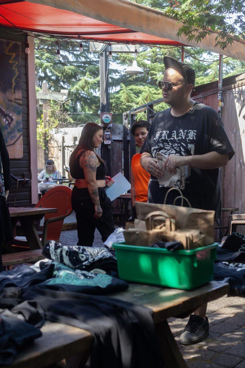 Attendees gather at the punk clothing swap at Sam’s Bonds Garage. The clothing swap encouraged people to bring their clothes to swap out with what they wanted from the tables. Alongside the swap, live music was present inside the bar. (Miles Cull/Emerald)