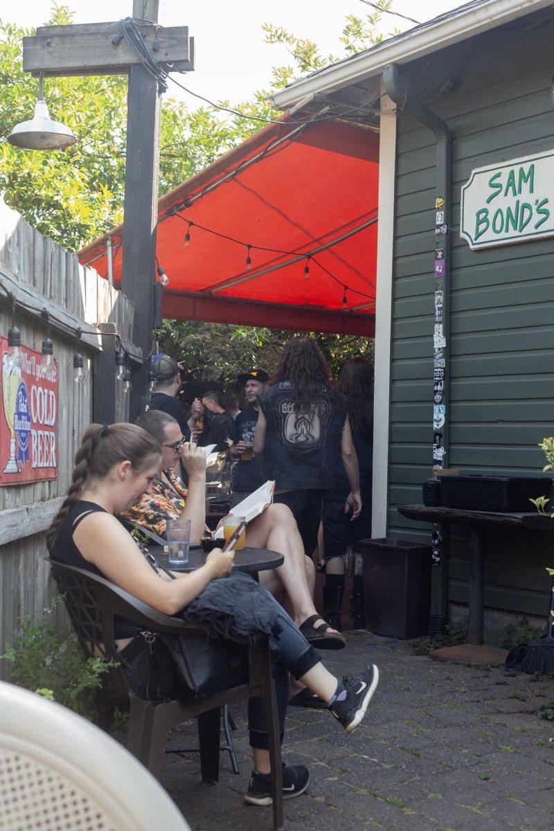 Attendees gather at the punk clothing swap at Sam’s Bonds Garage. The clothing swap encouraged people to bring their clothes to swap out with what they wanted from the tables. Alongside the swap, live music was present inside the bar. (Miles Cull/Emerald)