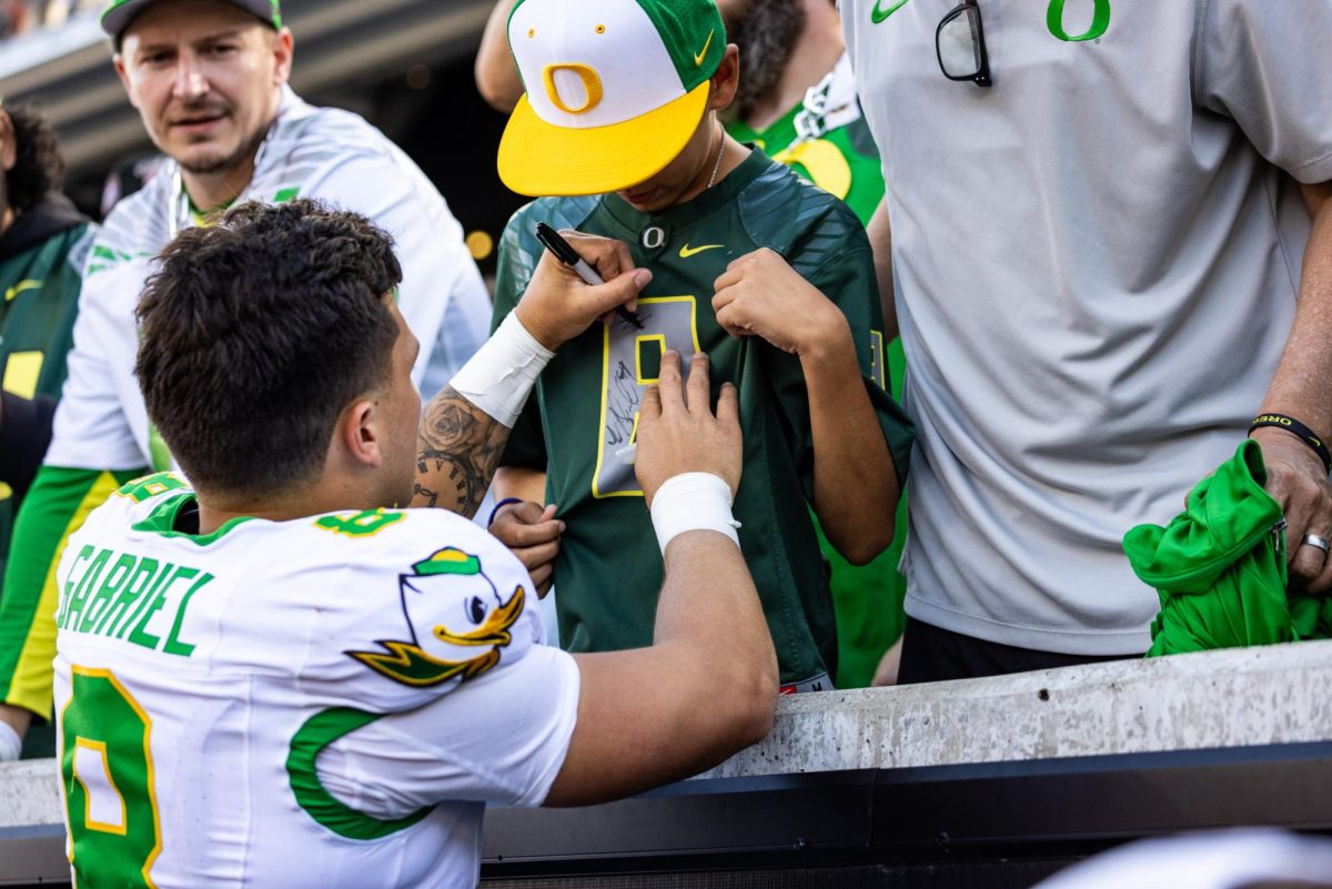 Dillon Gabriel (8) takes some time to sign some memorabilia for fans who braved the hostile Beaver environment to support their Ducks. The Oregon Ducks travel up to Corvallis to face their in-state rival the Oregon State Beavers on September 14th, 2024. (Jonathan Suni/Emerald)