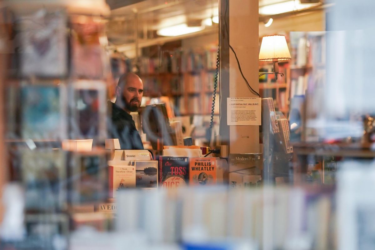 Seth Murray helping out a customer after they entered the book store. J Michaels Books, Eugene Oregon, Oct. 23 2024 (Eddie Bruning/Emerald)