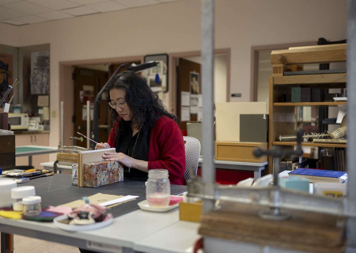 Victoria Wong, lead conservator at the Knight Library, removes the adhesive from the spine of a book on Oct. 30, 2024. (Alex Hernandez/Emerald)